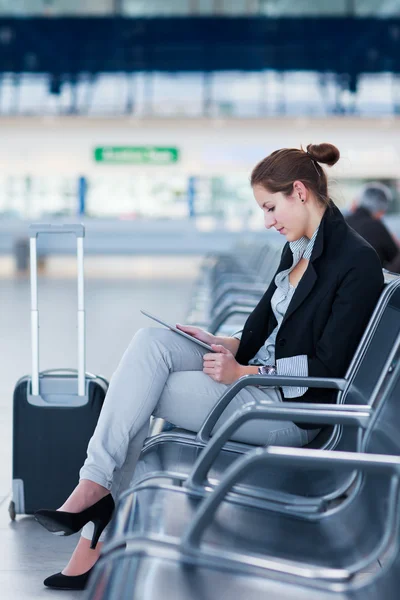 젊은 여성 승객은 공항에서 그녀의 태블릿 컴퓨터를 사용 하 여 — 스톡 사진
