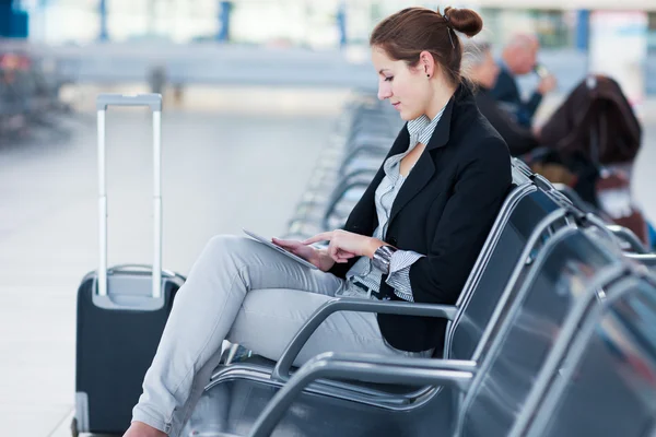 Jonge vrouwelijke passagier op de luchthaven, met behulp van haar tablet-pc — Stockfoto