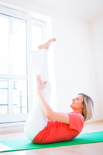 Csinos, fiatal nő csinálás jóga gyakorlás otthon — Stock Fotó