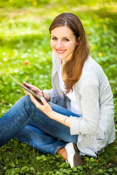 Giovane donna che utilizza il suo computer tablet mentre si rilassa all'aperto — Foto Stock