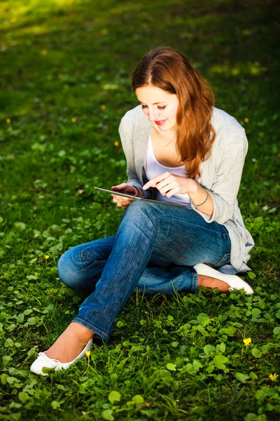 젊은 여성 야외에서 휴식 하는 동안 그녀의 태블릿 컴퓨터를 사용 하 여 — 스톡 사진