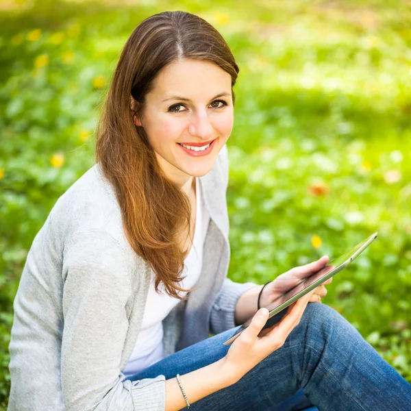 Młoda kobieta za pomocą jej komputer typu tablet podczas relaksu na świeżym powietrzu — Zdjęcie stockowe