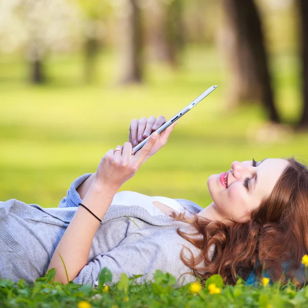 Mujer joven usando su tableta mientras se relaja al aire libre —  Fotos de Stock