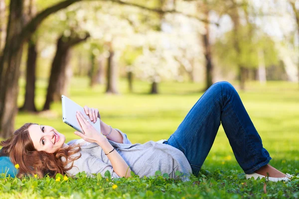 Junge Frau beim Entspannen im Freien mit ihrem Tablet-Computer — Stockfoto