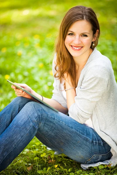 Ung kvinna med hennes tablett dator samtidigt avkopplande utomhus — Stockfoto