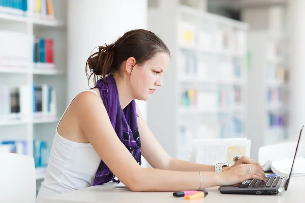 Pretty female college student studying in the university library — Stock Photo, Image