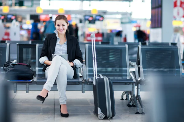 Junge Passagierin am Flughafen mit ihrem Tablet-Computer Stockbild