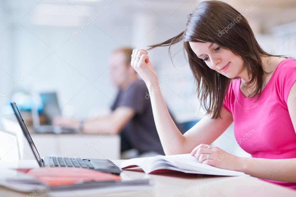 In the library - pretty female student with laptop and books