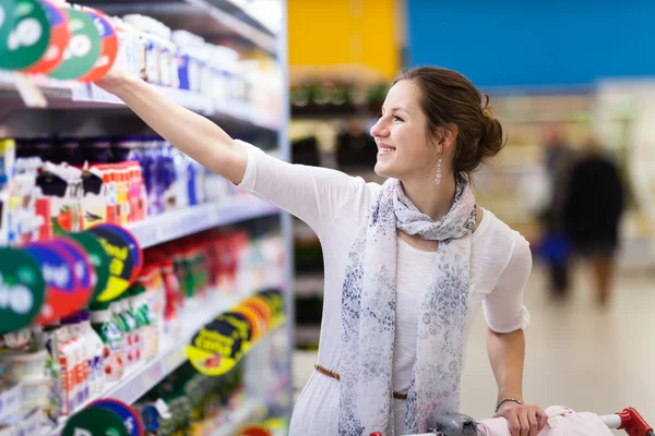Schöne junge Frau beim Einkaufen von Tagebuchprodukten in einem Lebensmittelgeschäft — Stockfoto