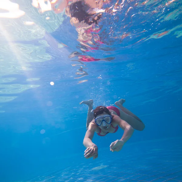 Simma under vattnet: ung kvinna simmar under vattnet i en pool — Stockfoto