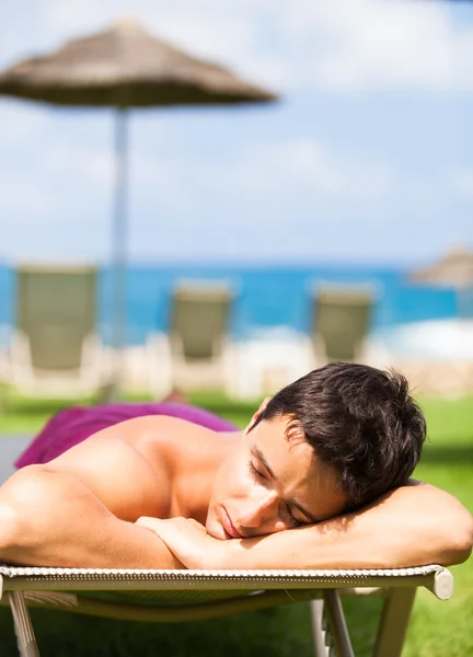 Jovem tomando banho de sol e relaxando em uma cadeira de praia — Fotografia de Stock