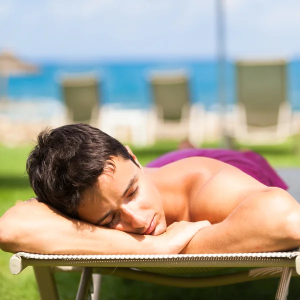 Hombre joven tomando el sol y relajarse en una tumbona — Foto de Stock