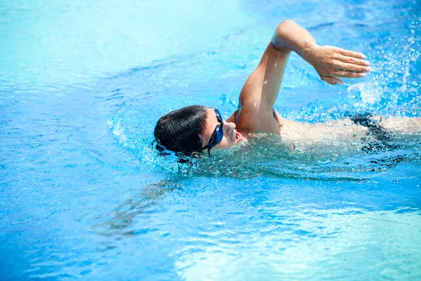 Ung man simmar det främre crawl i en pool — Stockfoto