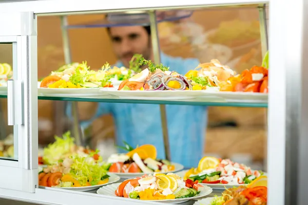 Jídelna potraviny displej mladý muž si vybrat salát — Stock fotografie