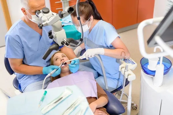 Odontólogo operando al paciente a través del microscopio —  Fotos de Stock