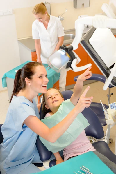 Улыбающийся дантист с ребенком на операции — стоковое фото