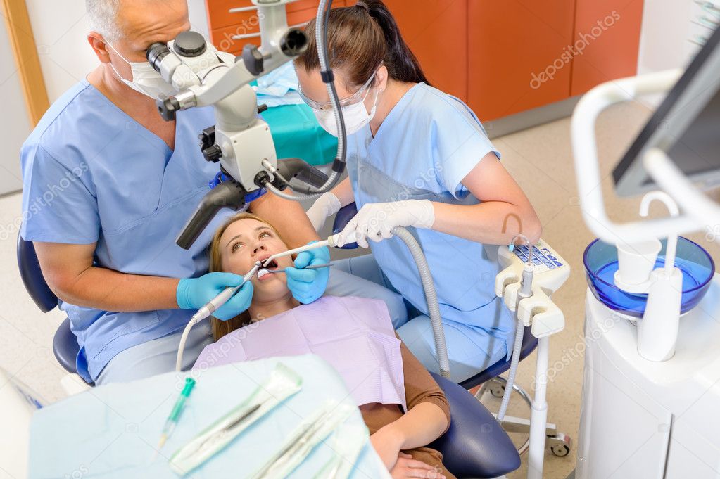Dentist operating patient through microscope