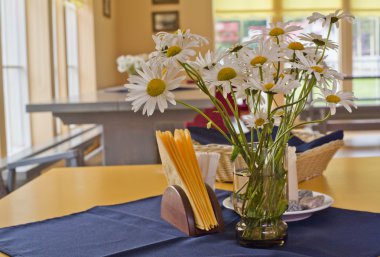 Daisys are placed in vase in restaurant clipart
