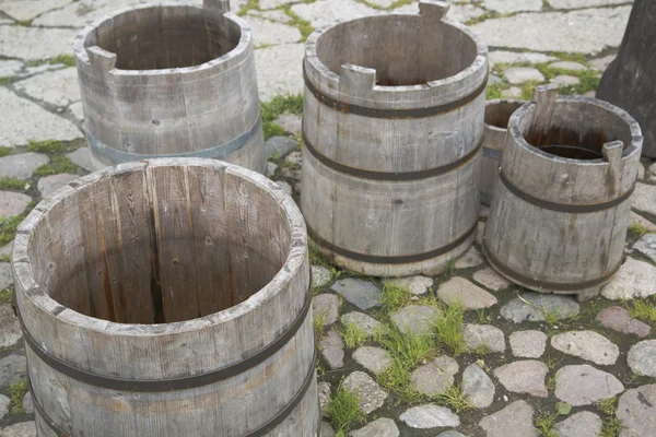 Quatre barils d'eau vides sur cour pierreuse — Photo