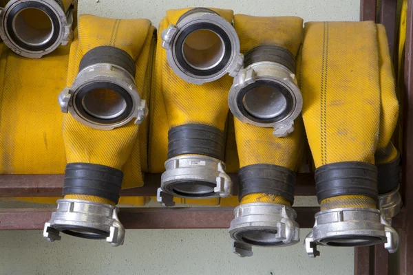 Zoomed yellow firehose are hanging in warehouse — Stock Photo, Image