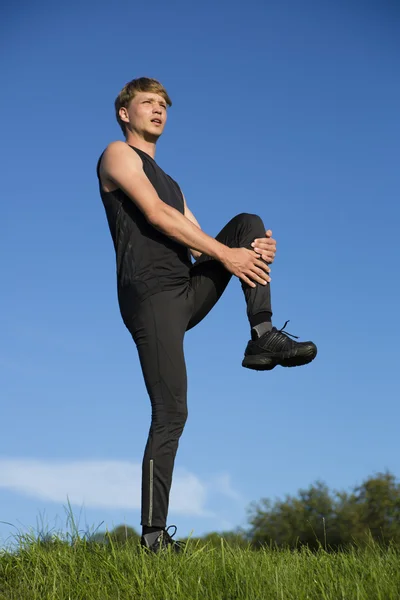 Sportler streckt linkes Bein halb — Stockfoto