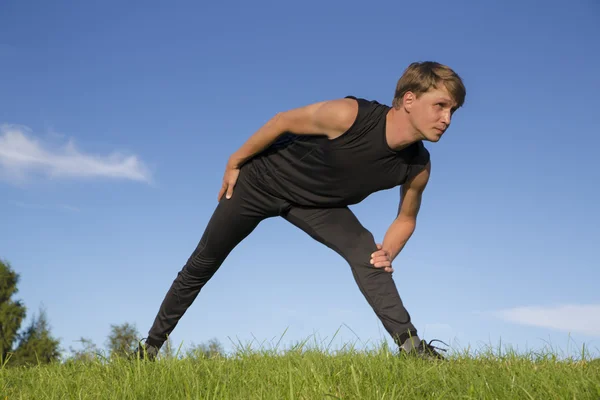 Sportsman making exercise movement to stretch leg — Stock Photo, Image