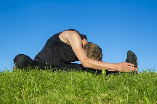 Sportsman är stretching på kulle — Stockfoto