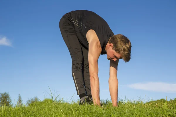 Sportsman making exercise movements to stretch muscles — Stock Photo, Image