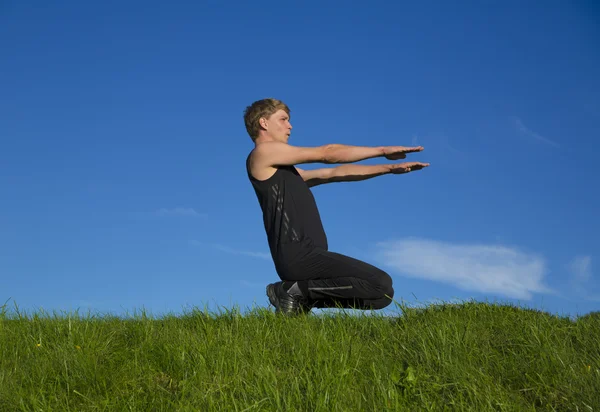 Sportsman is squatting on top of hill — Stock Photo, Image