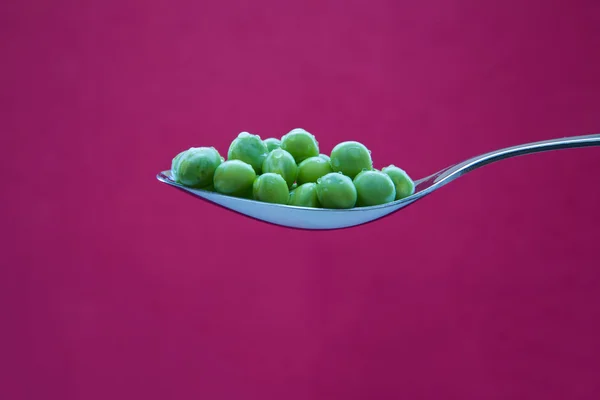 Grüne Erbsen auf verchromtem Metalllöffel — Stockfoto