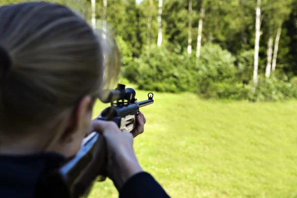 Woman targeting with hand weapon through sight — Stock Photo, Image