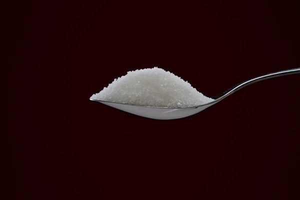 Kupie cukier na chromowanych łyżka — Zdjęcie stockowe