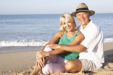 Senior couple sitting on beach relaxing clipart