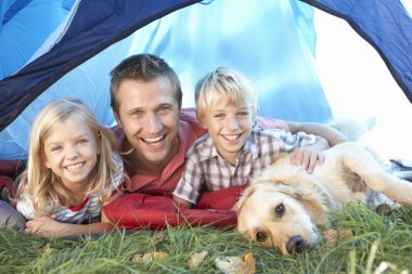 Young father poses with children in tent clipart