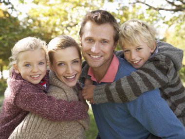 Young family pose in park clipart