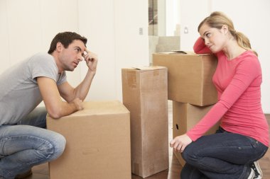 Young couple looking upset among boxes clipart