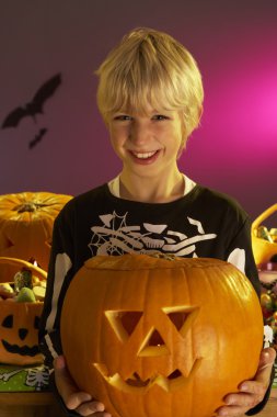 Halloween party with a boy holding carved pumpkin clipart