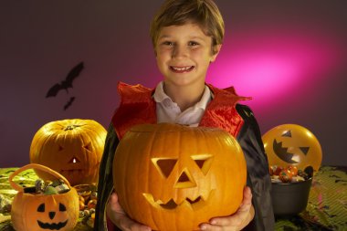 Halloween party with a boy child holding carved pumpkin clipart