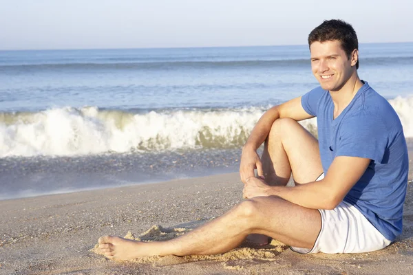 Чоловік сидить на пляжі розслабляючий — стокове фото
