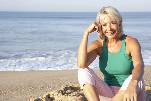 Mujer mayor sentada en la playa relajante —  Fotos de Stock