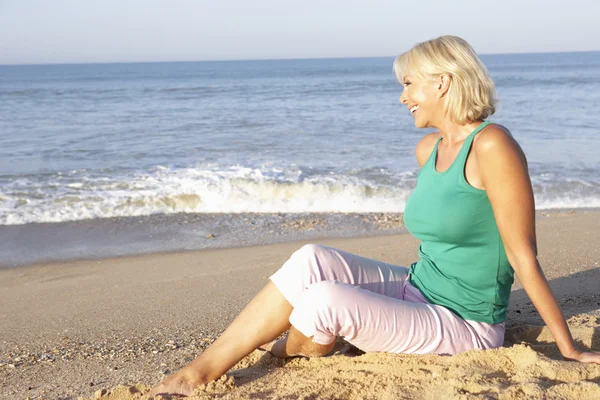 Senior woman sitting on beach relaxing — Stock Photo, Image