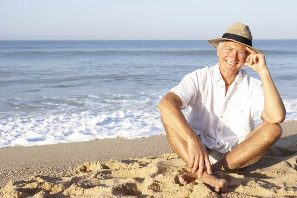 Senior man zit op het strand ontspannen — Stockfoto