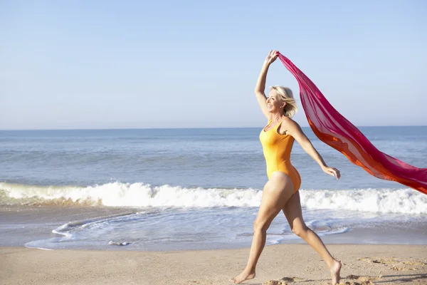 Senior vrouw lopen op strand — Stockfoto