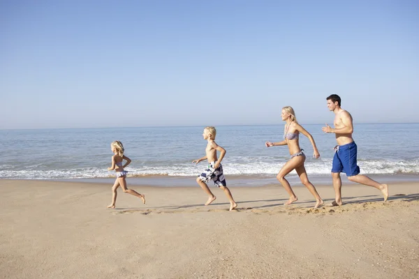 Jovem família correndo na praia — Fotografia de Stock