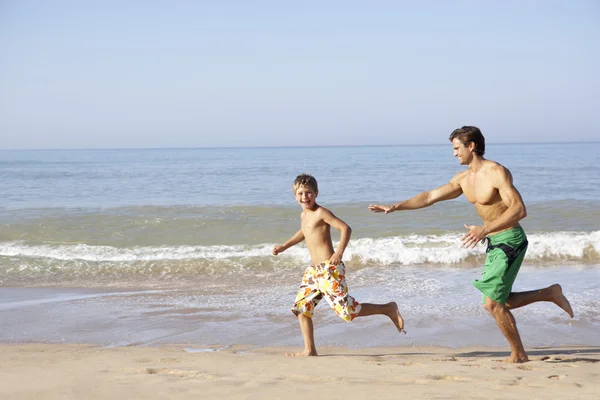 Father chasing young boy on beach — Stock Photo, Image