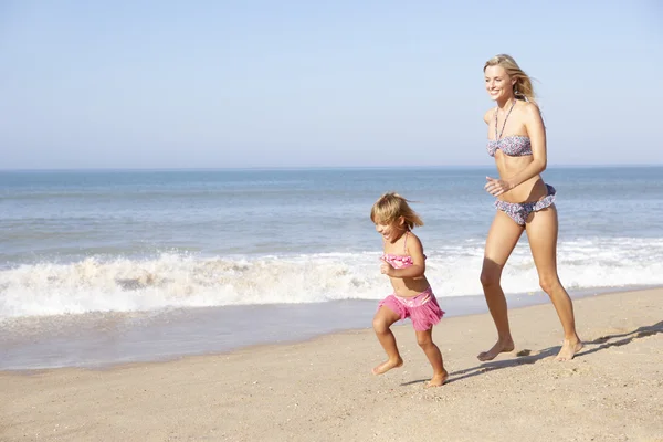 Moeder jong meisje jagen op strand — Stockfoto