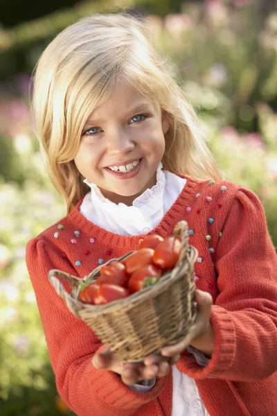 Young girl posing with tomatoes in garden — Stock Photo, Image