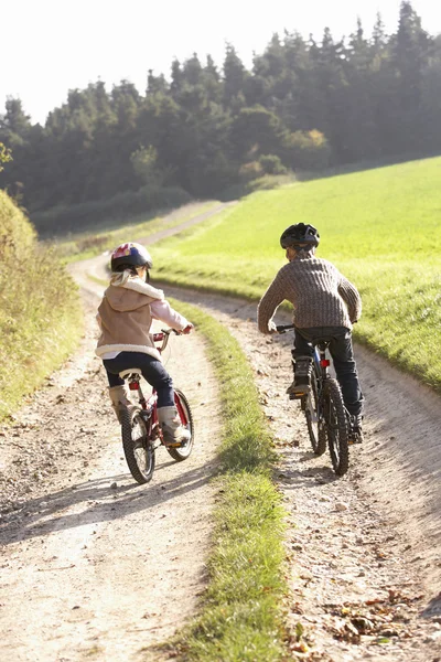 Two young children ride bicycles in park — Stock Photo, Image