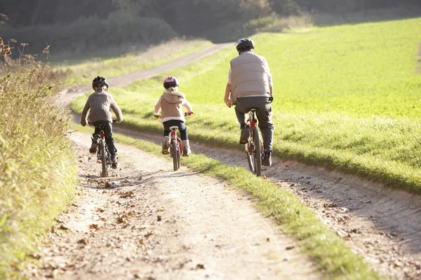 Junger Vater mit Kindern fährt Fahrrad im Park — Stockfoto