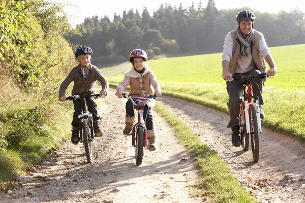 Mladý otec s dětmi jezdit na kole v parku — Stock fotografie